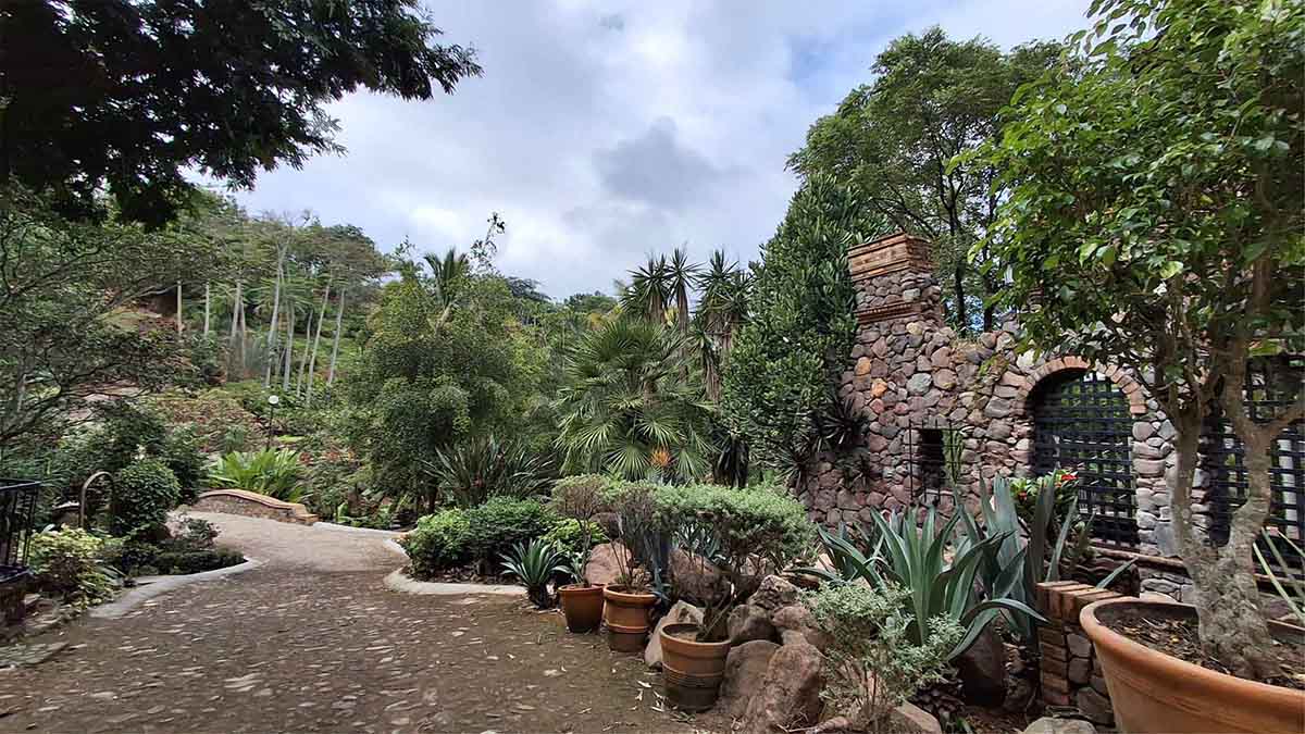 Entrada de Quinta Pichón presenta naturaleza entre árboles y jardineras, su arquitectura rústica está hecha de mampostería.