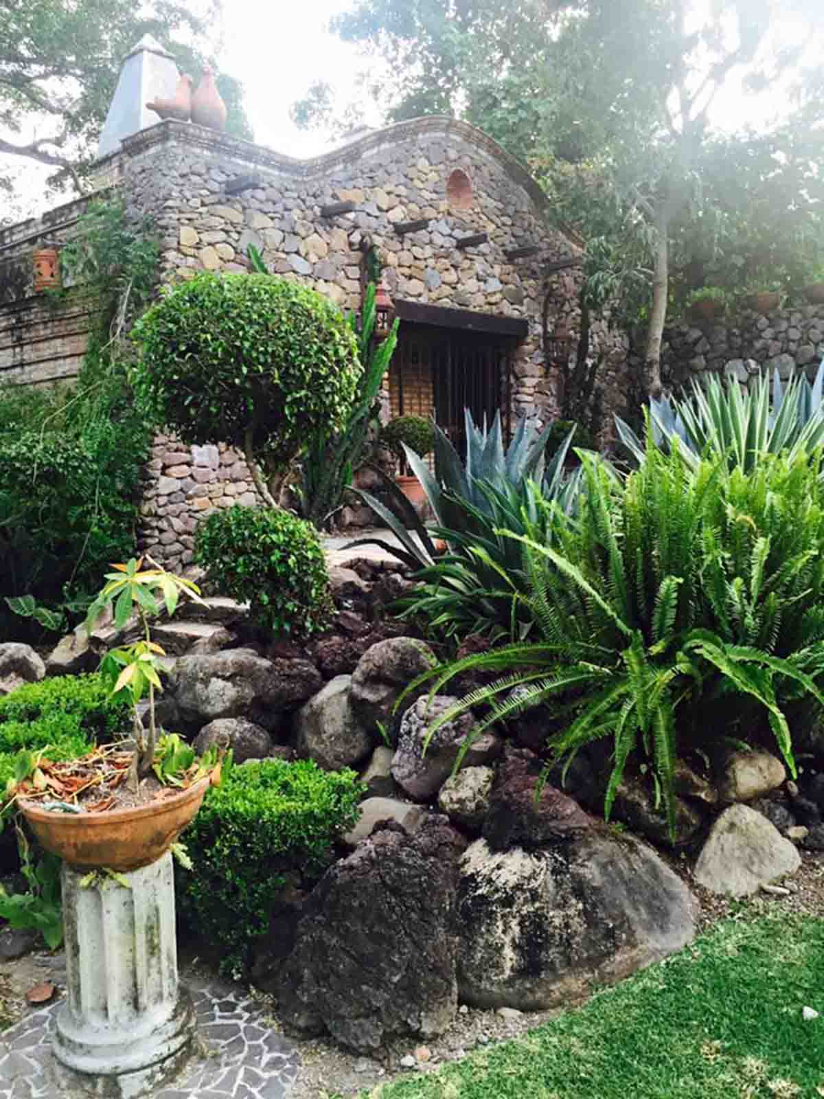 Jardines de Quinta Pichón con naturaleza abundante y arquitectura rústica hecha de mampostería.