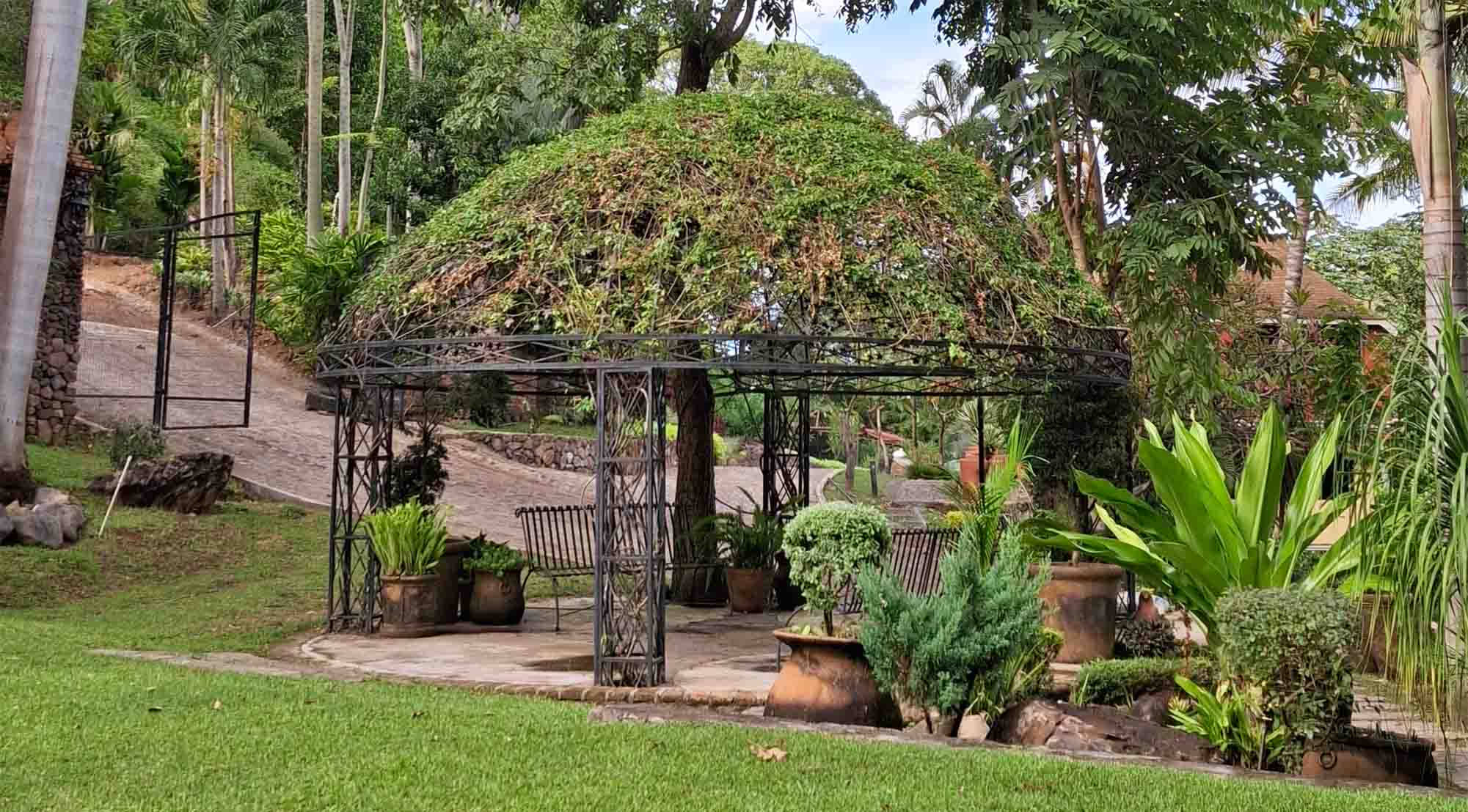 Jardín de Quinta Pichón rodeado de abundante naturaleza y en el centro una estructura metálica con forma circular.