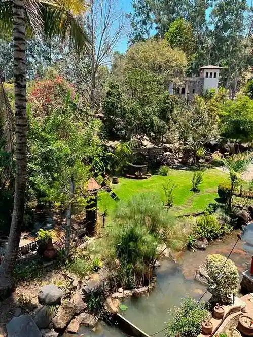 instalaciones de Quinta pichón, se visualiza uno de los jardines con un rio y arboles a su alrededor.