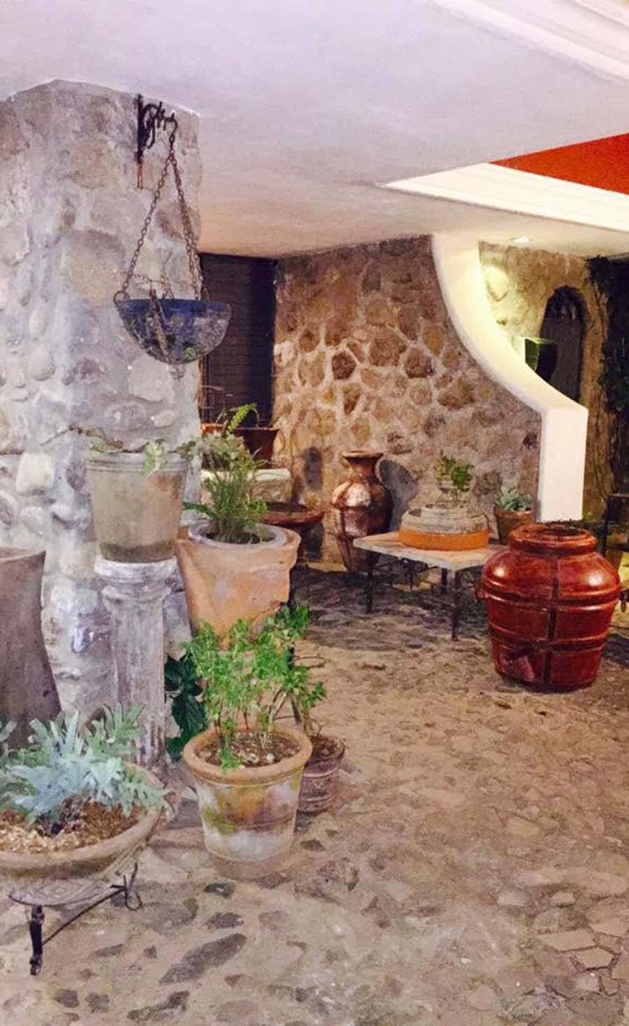 Patio de la zona de hospedaje de Quinta Pichón con un estilo rústico tradicional con acabados en mampostería y macetas para decoración.