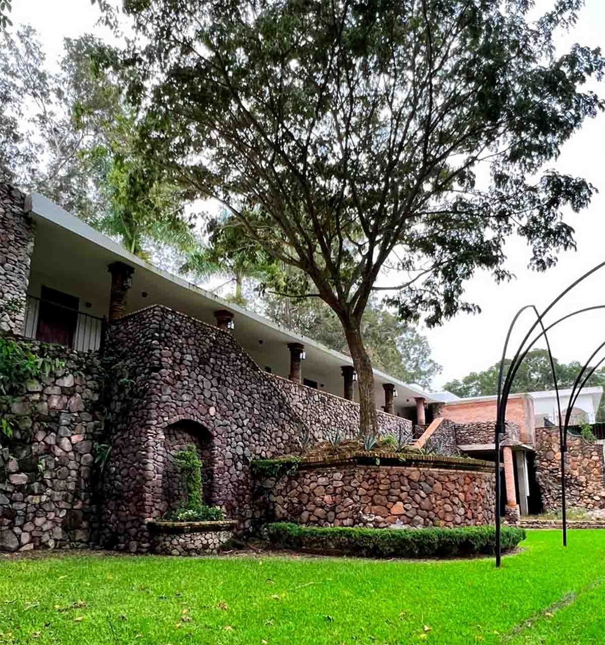 Zona de habitaciones de hotelería Quinta Pichón con un gran jardín y fachada rústica.