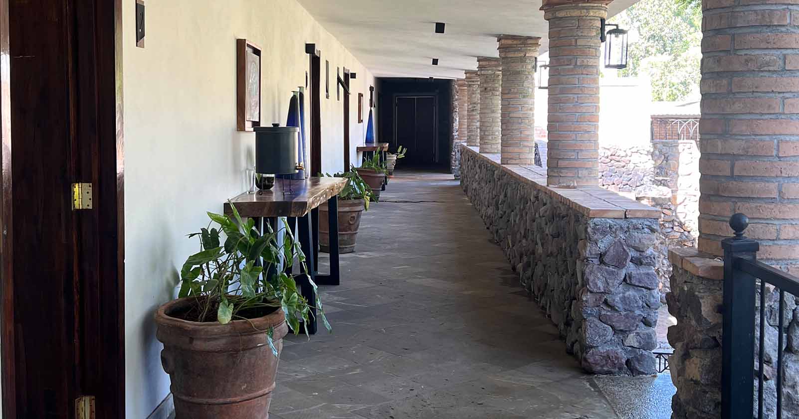 Pasillo de las habitaciones de la zona para huéspedes de Quinta Pichón, la arquitectura tiene partes decoradas con piedra de manera irregular que le dan un estilo rustico.