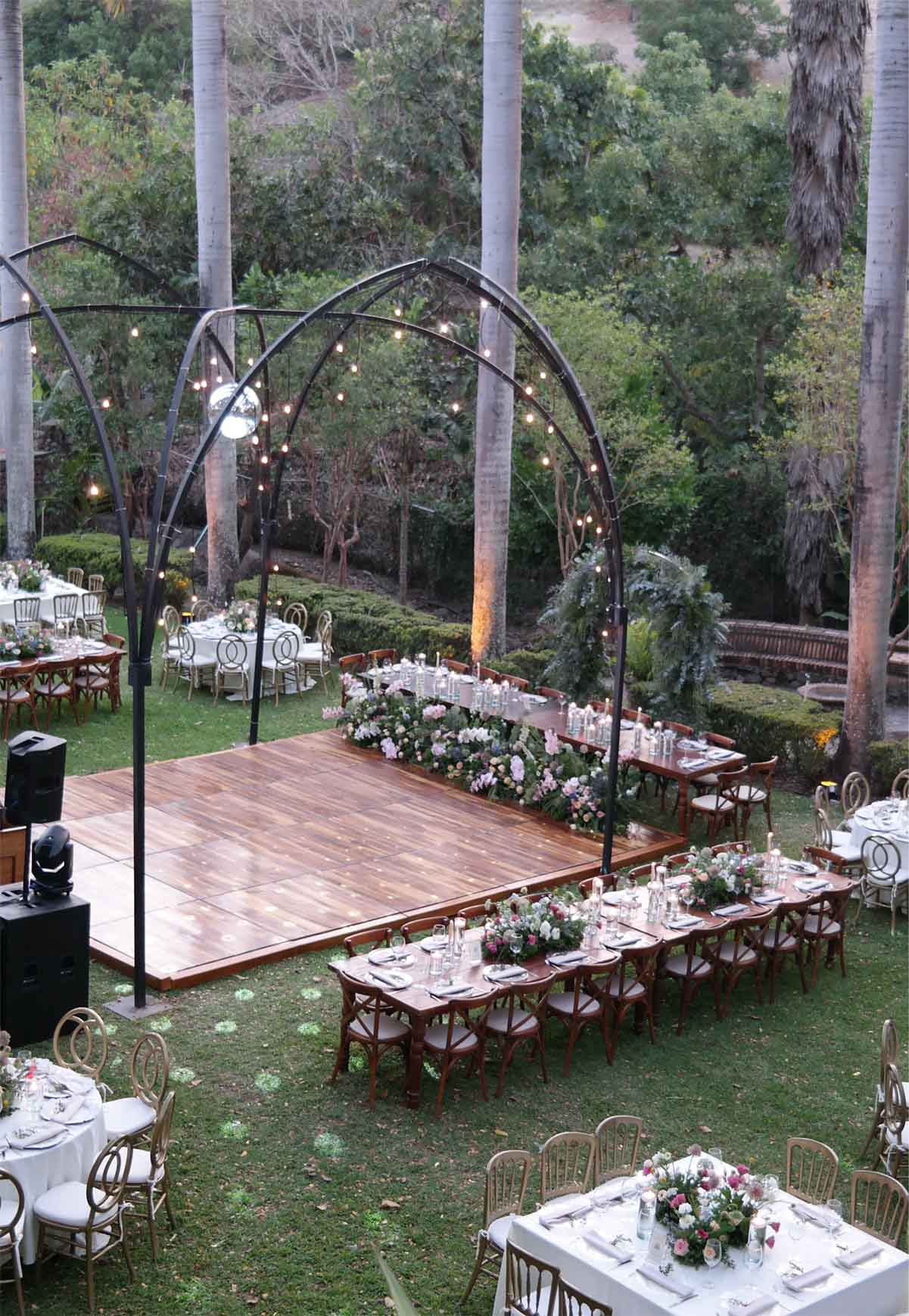 Jardín de Quinta Pichón con mobiliario y decoración para un evento social con un gran arco metálico en el centro decorado.