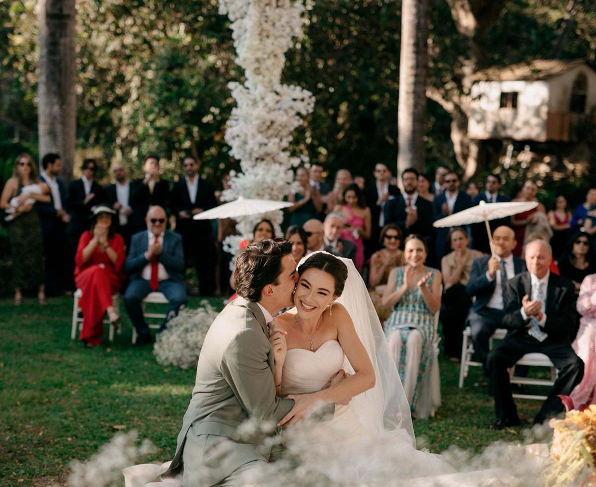 Pareja de novios celebrando su boda en uno de los jardines de Quinta Pichón, abrazados en el centro mientras los invitados celebran su unión.