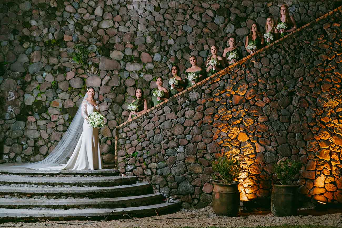 Novia acompañada de sus damas de honor llevan vestidos para celebrar una boda, la novia viste de blanco y las damas de color verde.