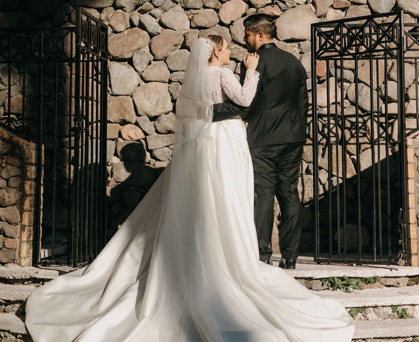 Pareja de novios en su sesión de fotos en Quinta Pichón, visten con ropa para boda ella su vestido blanco y el traje negro elegante.