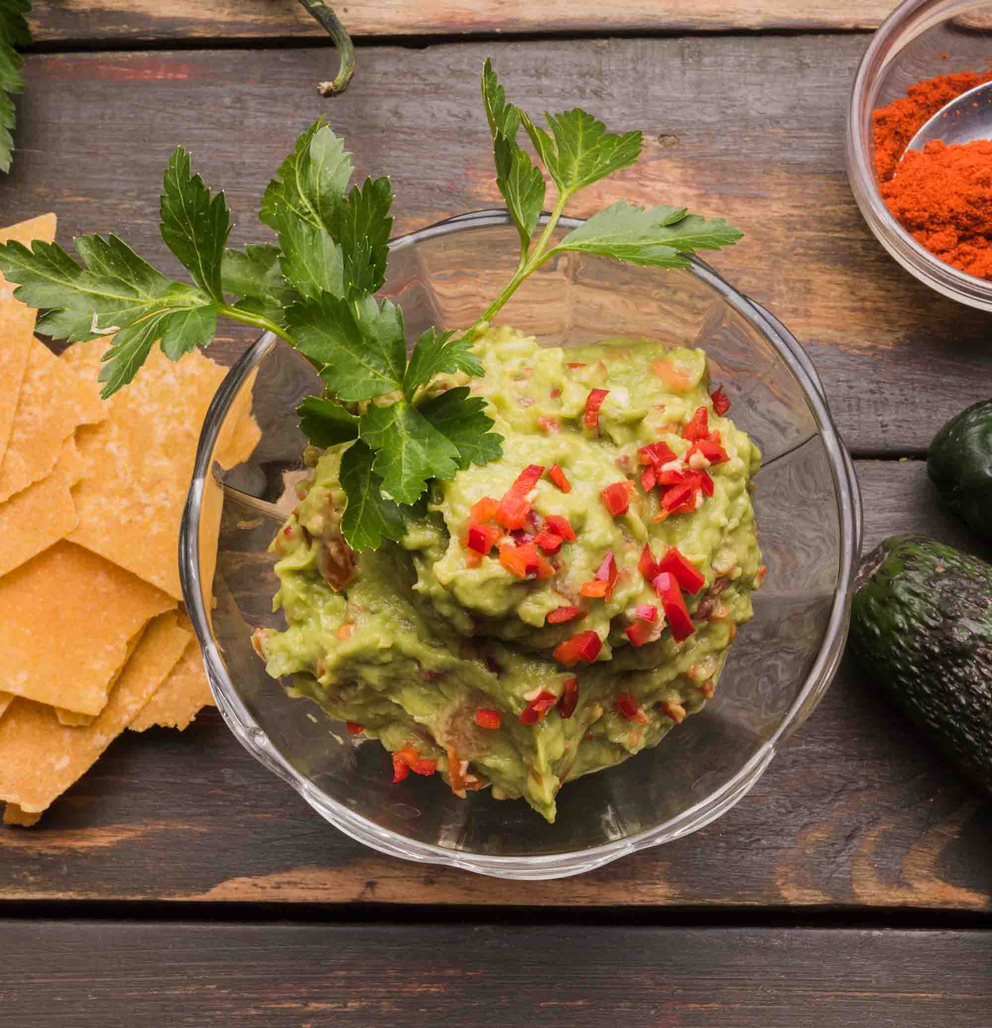 Salsa de aguacate, chiles y pimiento rojo servida en un recipiente de cristal.