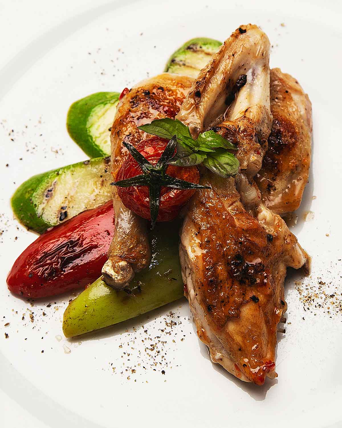 Pollo frito acompañado de calabazas y pimientos rojos sasonado con pimienta molida.