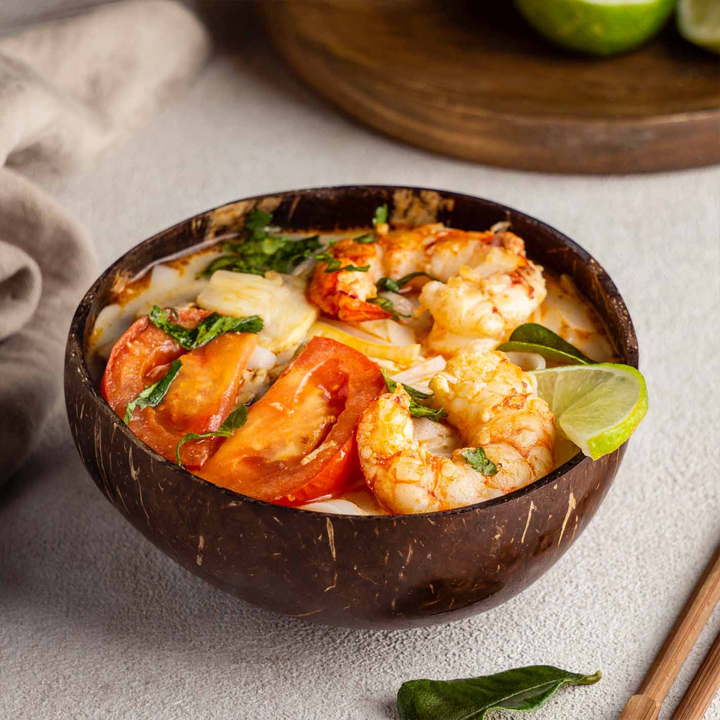 Sopa de camarones y verduras servido en un plato de madera.