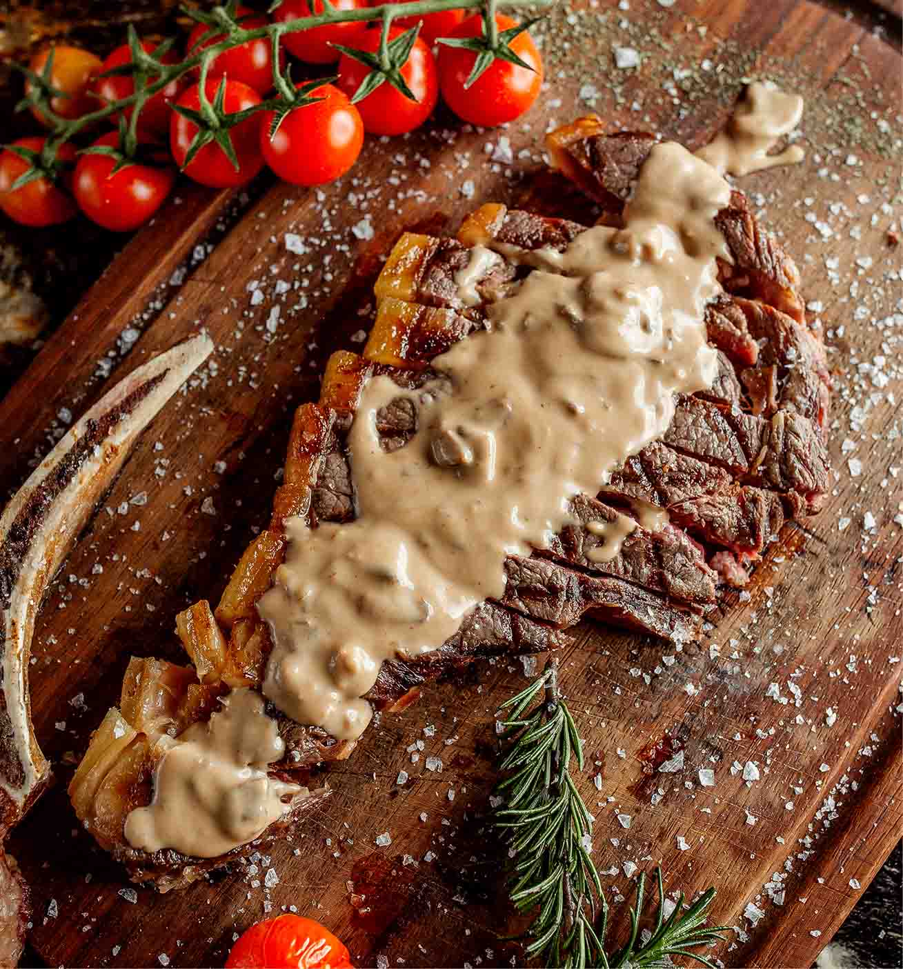Carne asada con aderezo y sazonada con sal y pimienta, servida en una tablilla con vegetales para decorar.