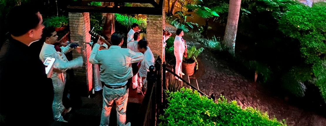 Grupo de mariachis asistiendo a un evento social para cantar que se celebra qen un jardin.