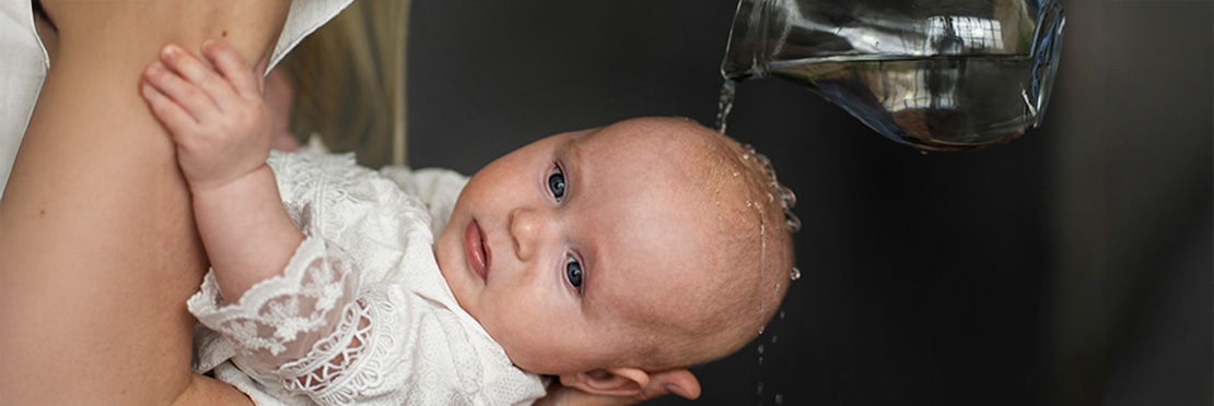 Bebe siendo bautizado, un padre derrama gua bendita sobre su cabeza para completar el rito.